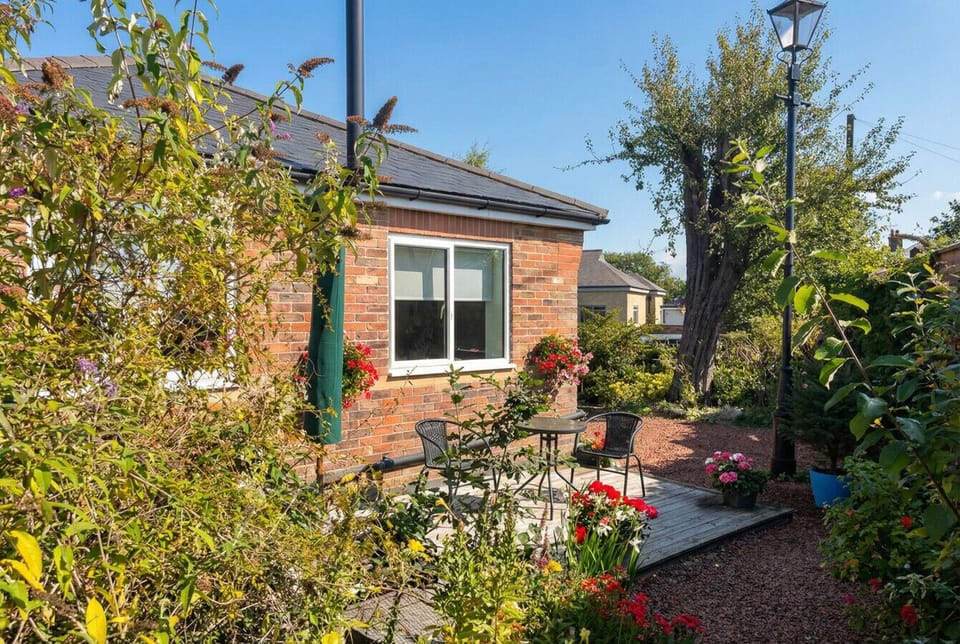 Lush cottage gardens and a vintage lamp post frame the private rear terrace perfectly.