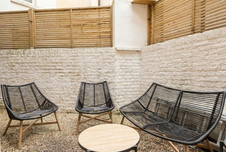 Private courtyard with rattan seating and timber screens, your own quiet corner in West Kensington.