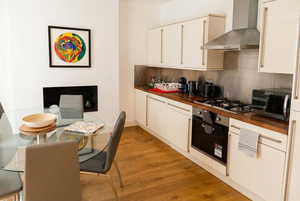 Open-plan kitchen and dining room where colourful art and a gas range make cooking feel effortless.