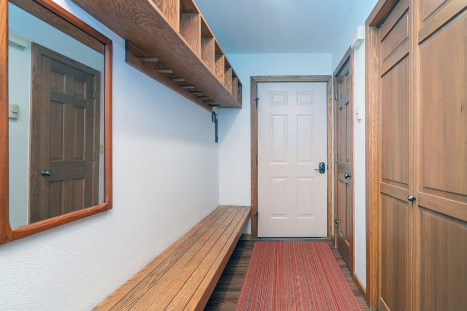 A warm, organized entryway welcomes you with rich wood tones, overhead storage cubbies, a built-in bench for easy gear prep, and plenty of closet space to keep your retreat tidy and inviting.