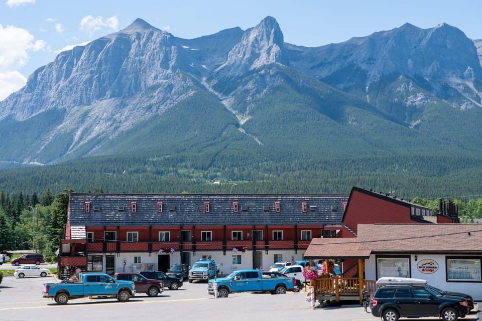 Lodge exterior surrounded by trees, with the Rocky Mountain peaks rising behind