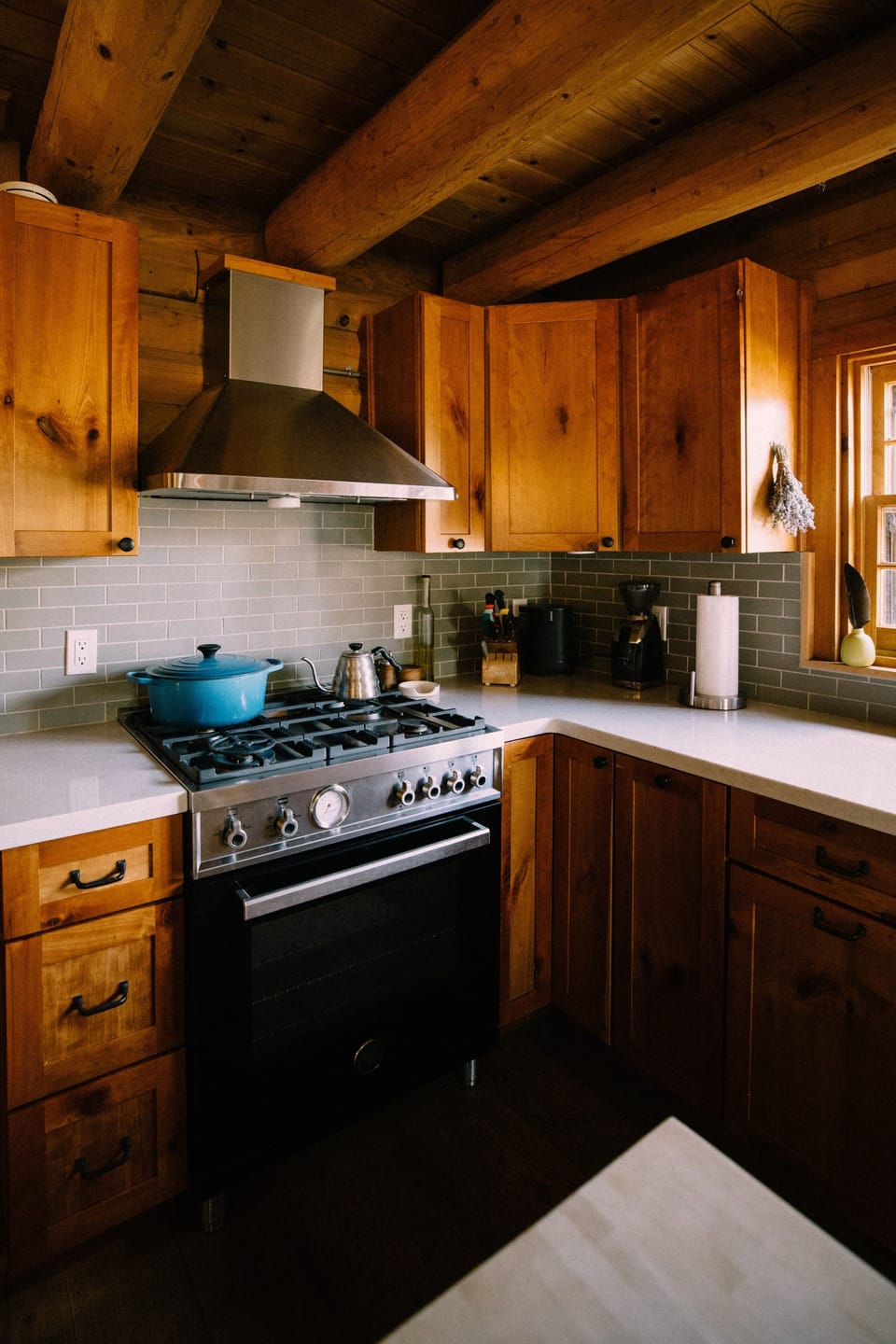 Gas range, quartz counters and sage-green tile in the updated kitchen