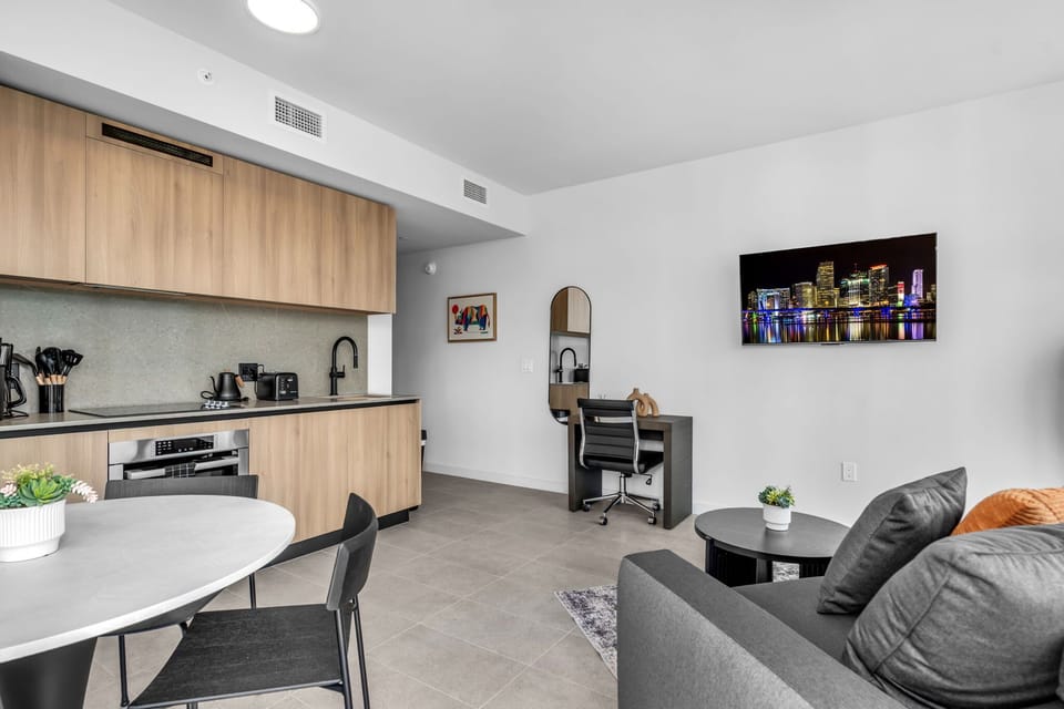 Dine in style! This chic white round table and sleek chairs sit perfectly between the modern kitchen and vibrant living space. It's a bright, versatile spot for enjoying meals or working, all while soaked in natural light.