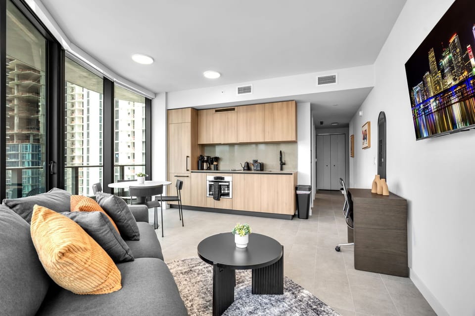 Relax in style! This bright, open-concept space features a sleek modern kitchen, a cozy lounge area with a Smart TV, and a dedicated workspace. Floor-to-ceiling windows flood the room with natural light. Perfect for working or unwinding!