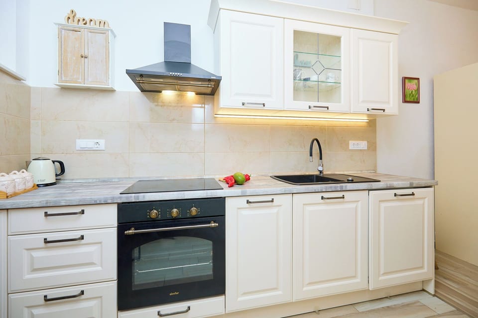 The modern, fully equipped kitchen features sleek black appliances and cream-colored cabinetry, perfect for preparing meals.