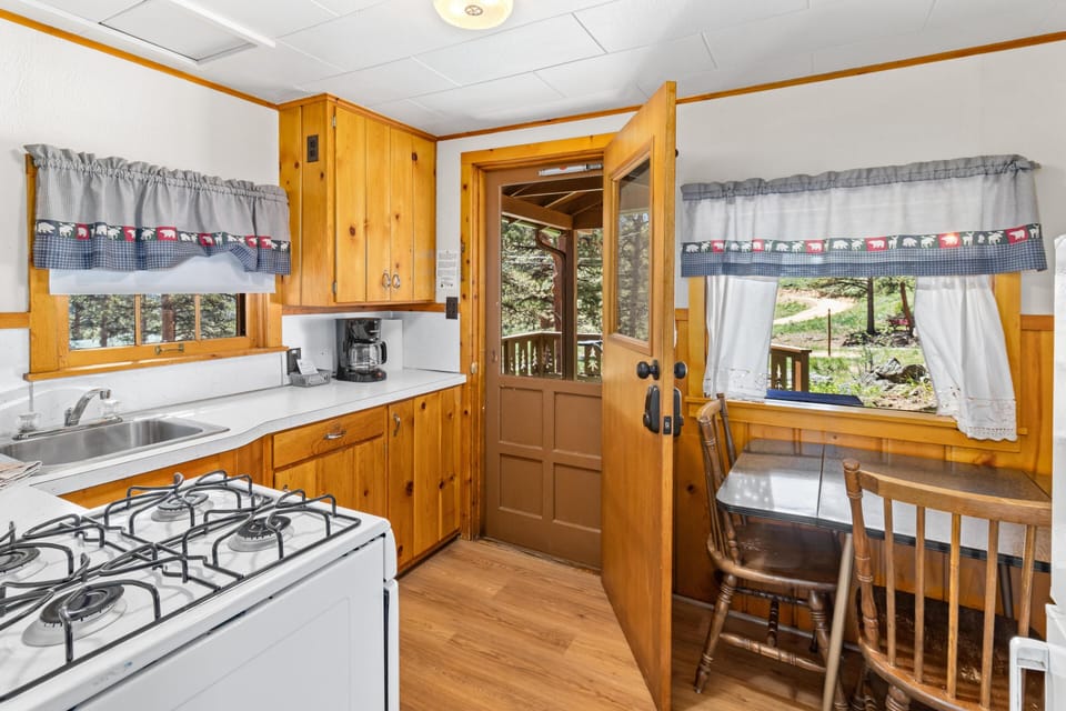 Kitchen nook with wood-paneled walls, a small dining table, and a door opening to the outdoor deck.
