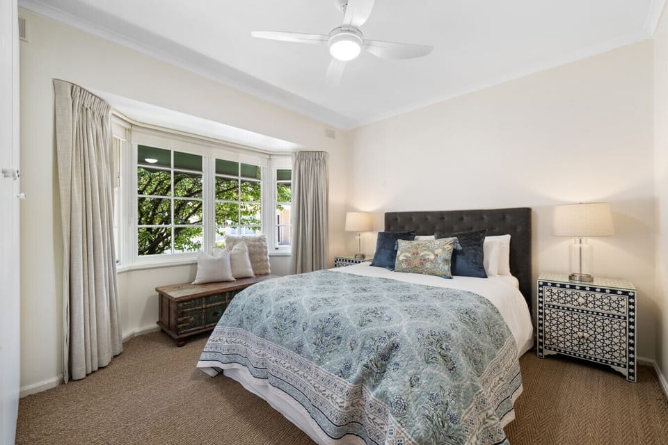 Wake gently to soft natural light in this peaceful queen bedroom. A cosy space to start the day, with leafy views just beyond the bay window.
