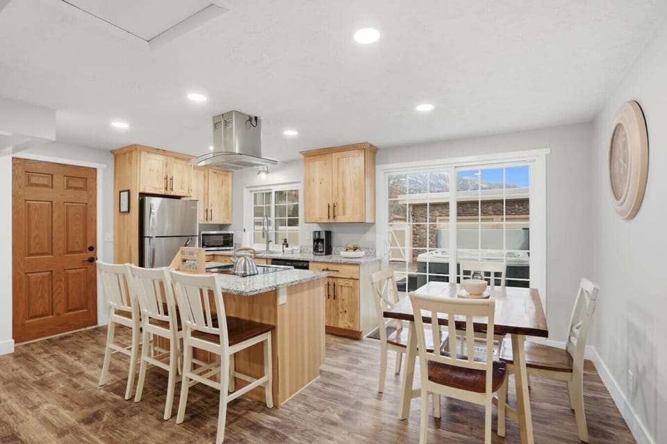 Modern kitchen and dining area with island seating and backyard views