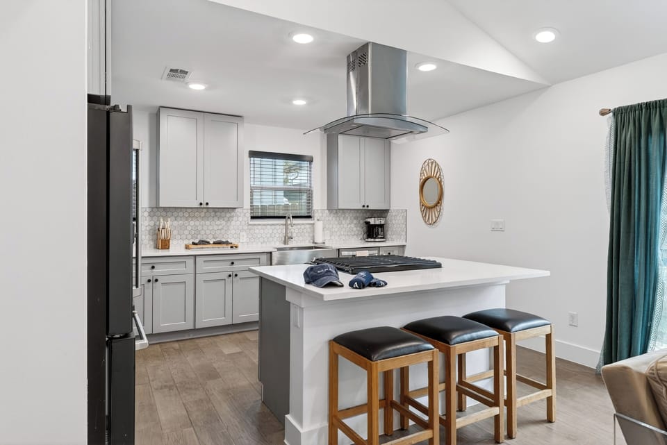 Bright workspace highlighting the stainless steel range hood and tiled backsplash.