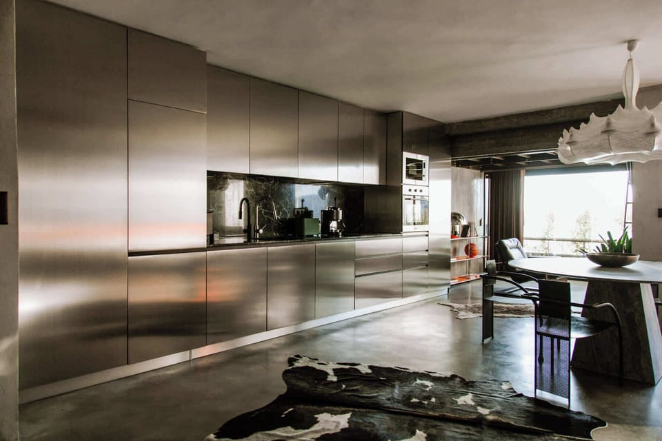 Sleek stainless-steel kitchen wall with integrated appliances and minimalist architectural design.