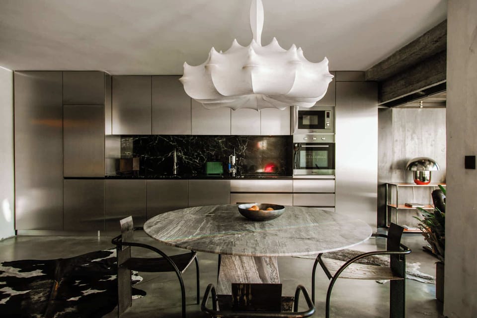Modern dining area set beside the designer kitchen with sculptural chandelier lighting.