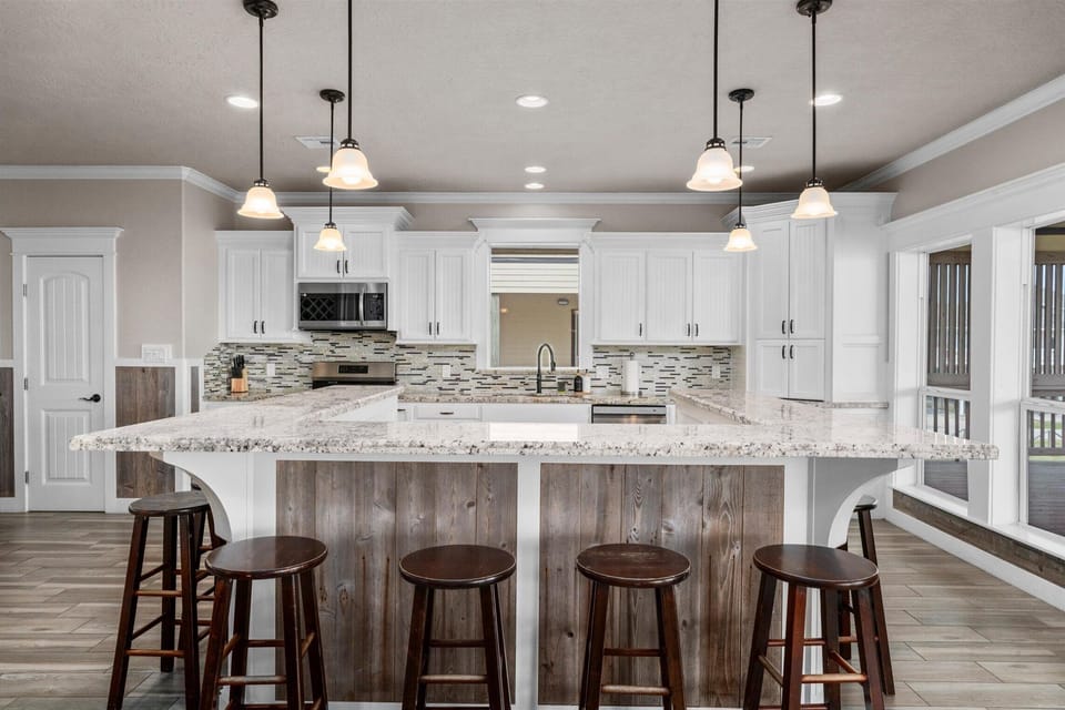 Modern kitchen with large island, bar seating, pendant lighting, and white cabinetry