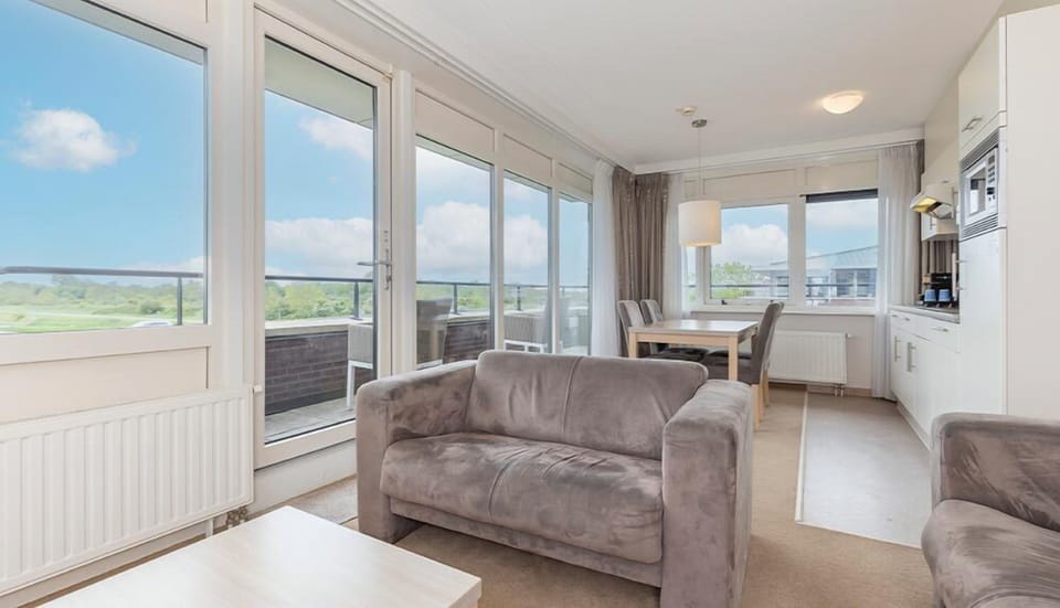 Lounge in sunlit comfort beside expansive windows and balcony doors.