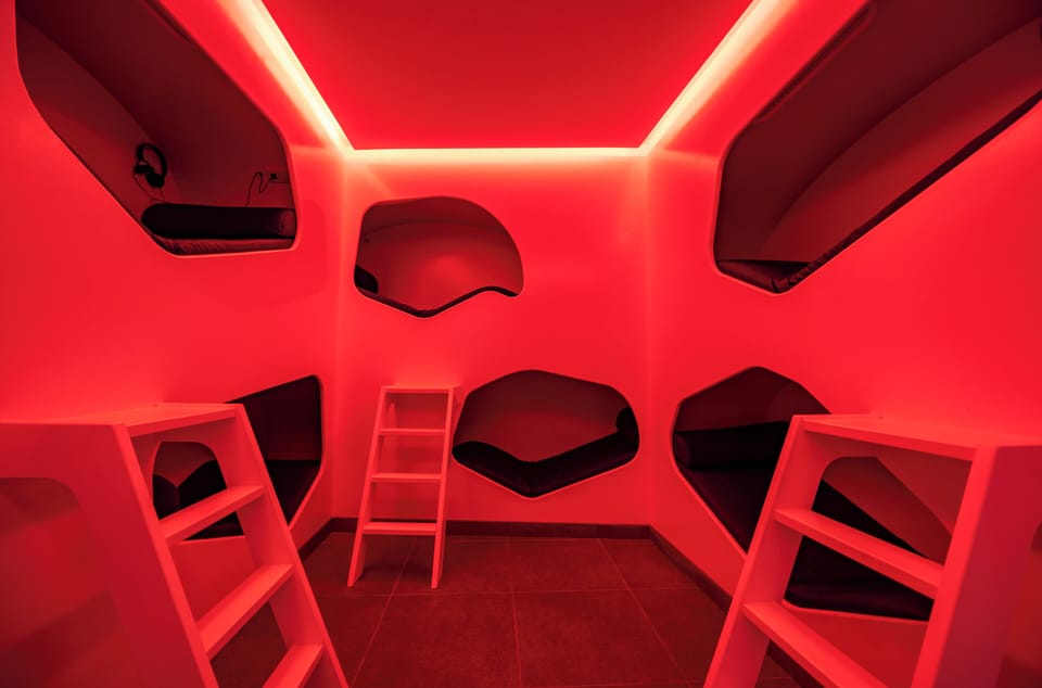 Drift into quiet in futuristic sleeping pods, cocooned in light.