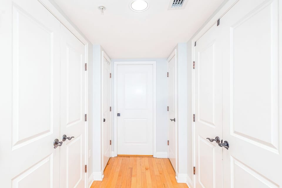 Step into your private hallway with gleaming hardwood floors and crisp white doors leading to your closets and bath.
