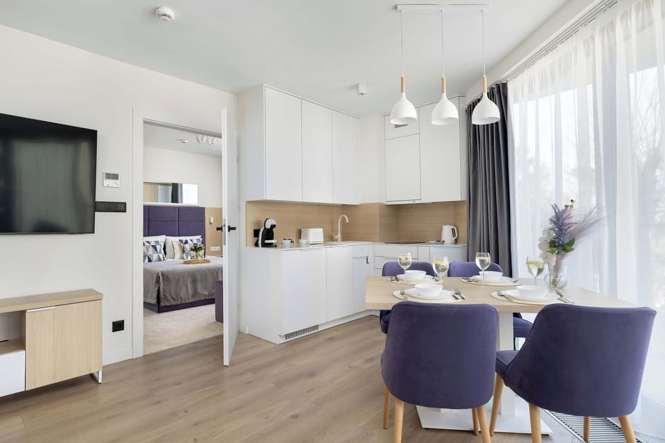 A glass of white wine and a small plate of snacks are carefully placed on the wooden dining table. This setting suggests a quiet moment of relaxation in a comfortable home environment.