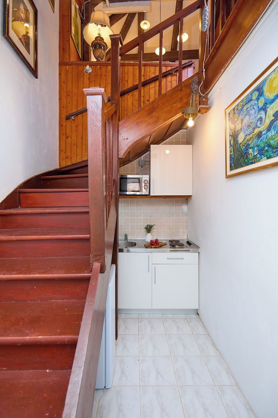 Discover the unique two-story layout of this heritage apartment. A compact, modern kitchenette is cleverly tucked beneath a charming wooden staircase.