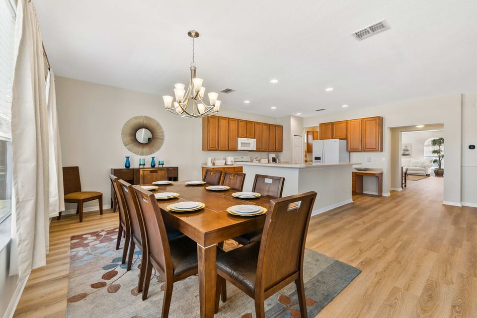 Spacious dining area with a large wooden table and open kitchen featuring warm cabinetry.