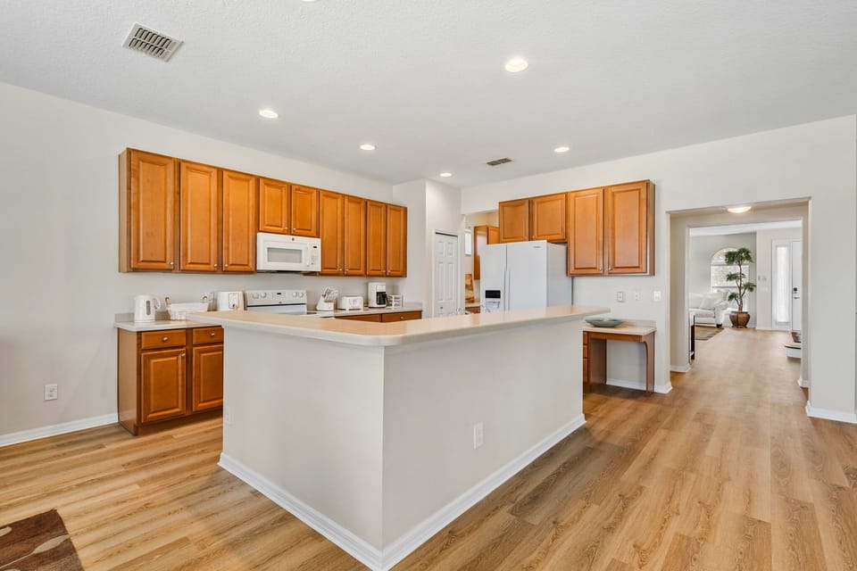 Spacious kitchen with wooden cabinets and a breakfast bar overlooking the living area.