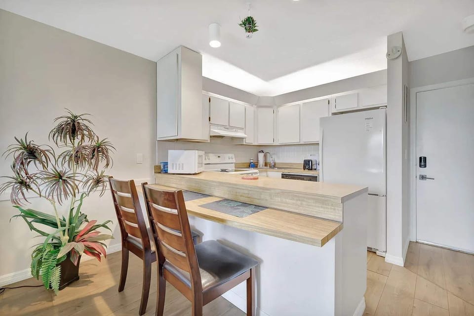 Modern kitchen with bar seating, fully stocked with cooking utensils and dishware.