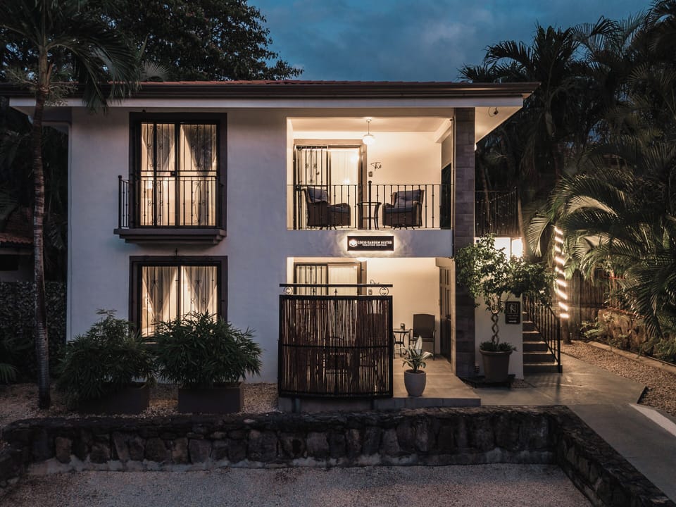 Arrive after sunset to a softly illuminated pathway lined with tropical greenery. 
