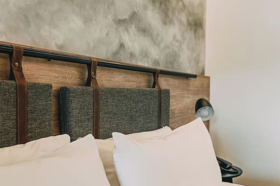 Admire thoughtful headboard details beside cozy bedside lighting.