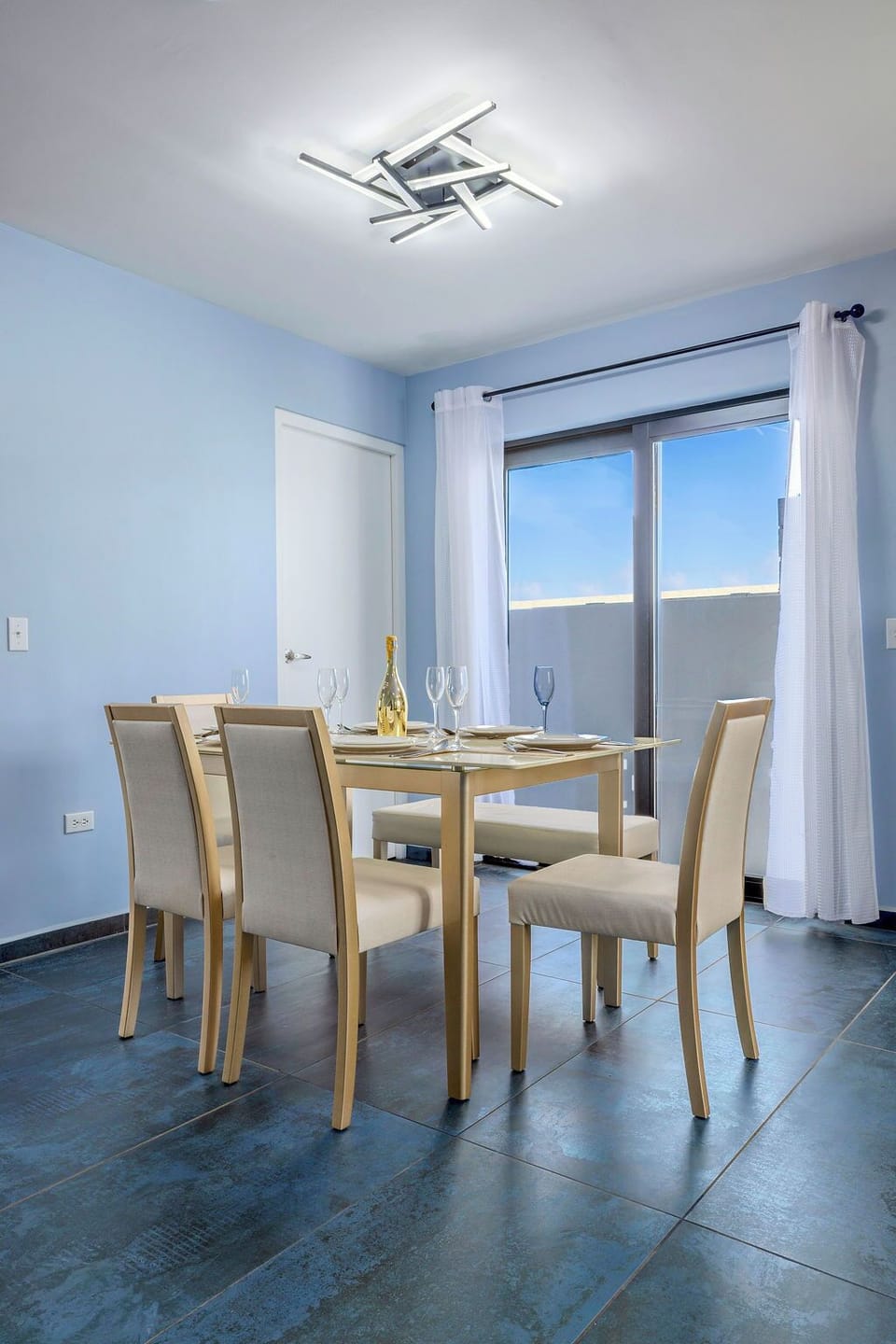 Start your day in our bright, open-plan space. Enjoy breakfast at the sleek glass dining table under a modern light fixture, with comfortable seating and large glass doors that fill the room with natural light.