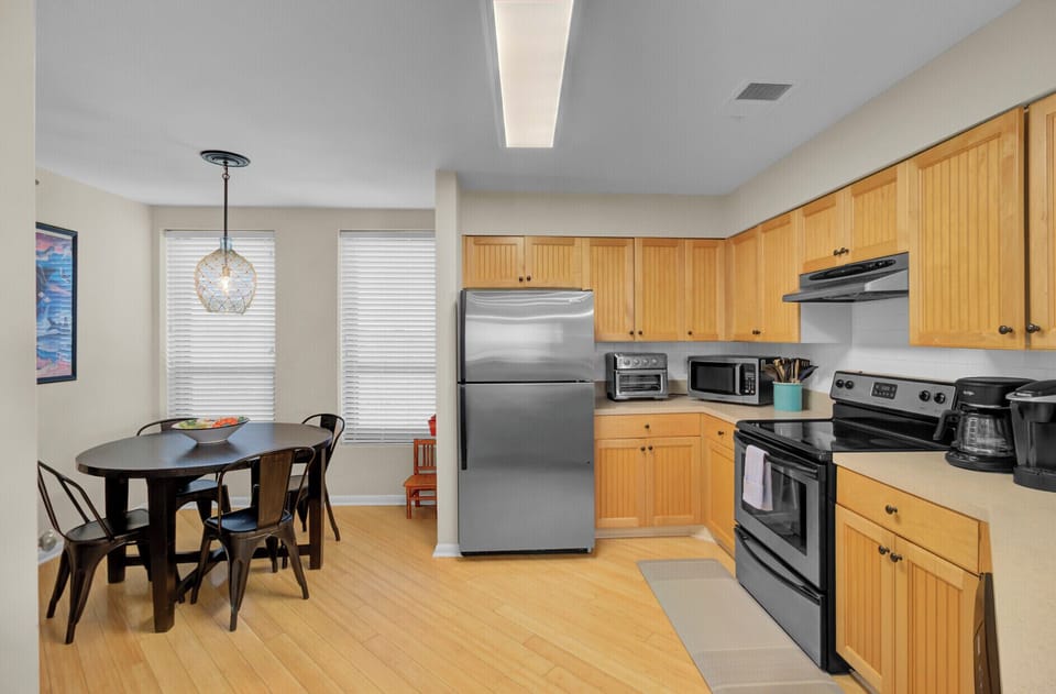 View of the stainless steel refrigerator and the transition to the dining area.