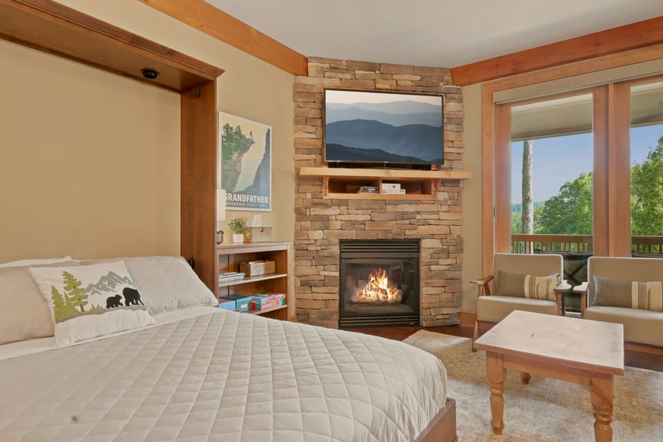 Wake up facing the gas fire glowing beneath the mounted TV, with glass doors just past the mantel opening onto the balcony and a pair of armchairs positioned to catch the tree-lined mountain view outside your window.