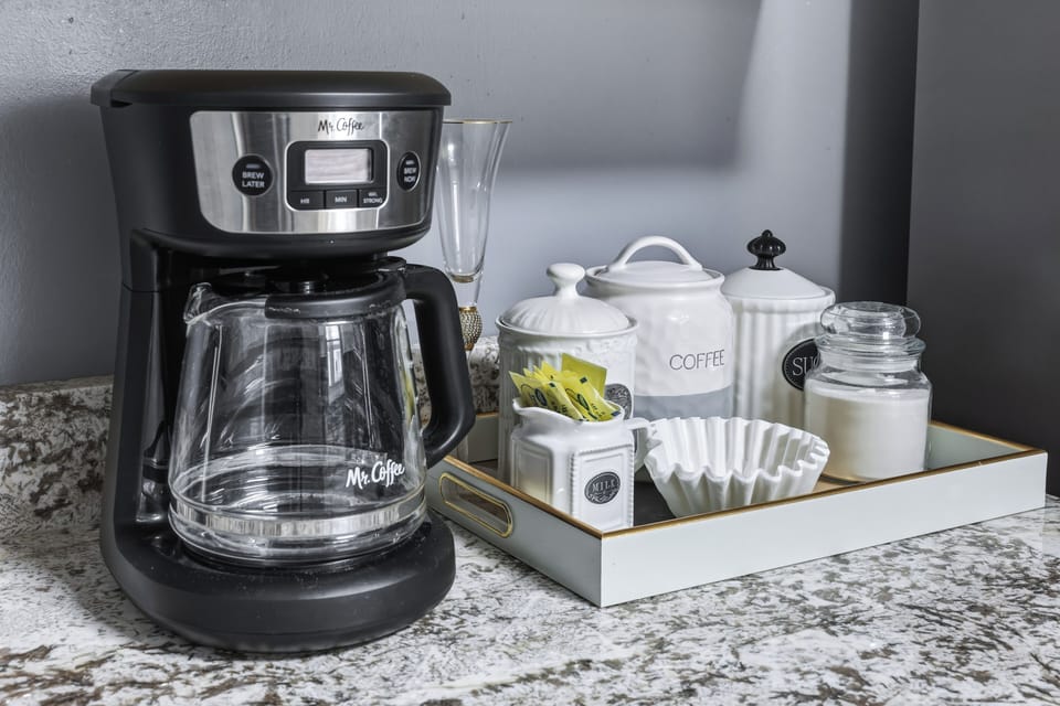 Coffee bar included with a drip coffee machine with complimentary coffee, tea, sugar, cream, and sweetener