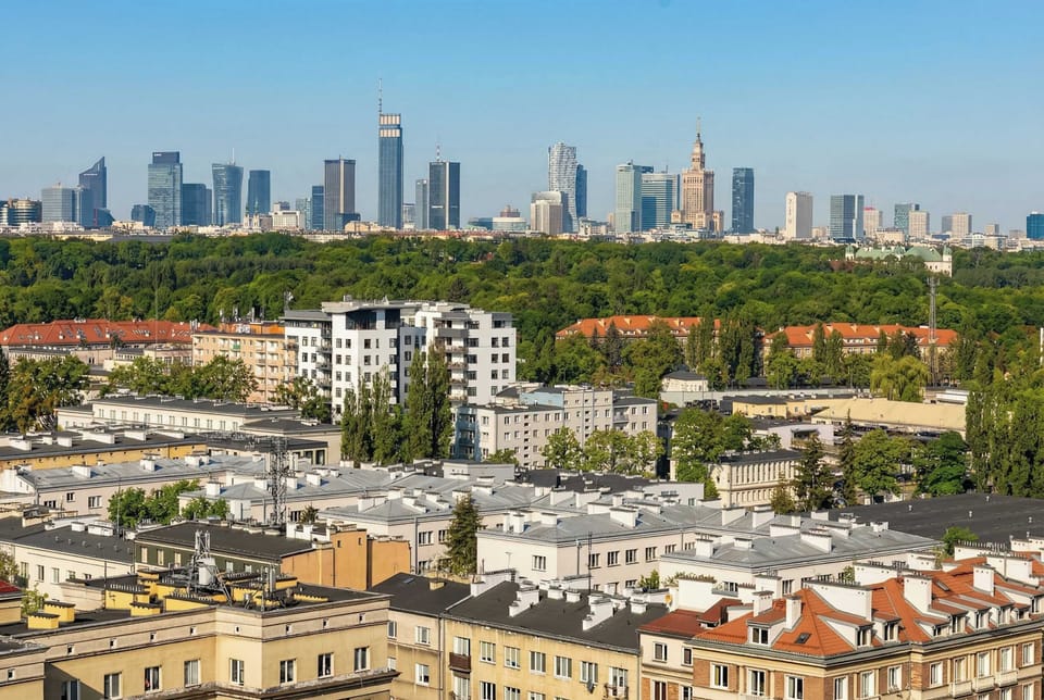 The view reveals a stunning panorama of the city skyline, with lush green parks in the foreground and skyscrapers in the distance.