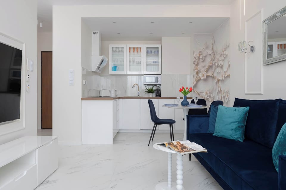 The kitchenette's white lacquered cabinets contrast beautifully with the wooden countertops, offering a clean and organized cooking space.