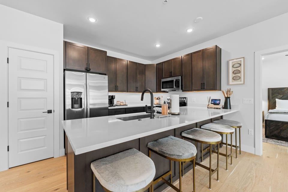 Full kitchen with stainless steel appliances, and a breakfast bar with seating for five.