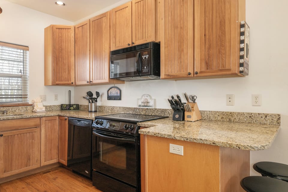 Your fully equipped kitchen at Granby Lake Shore Estates Townhome 5  features warm wood cabinets, granite countertops, and modern appliances for preparing delicious home-cooked meals.