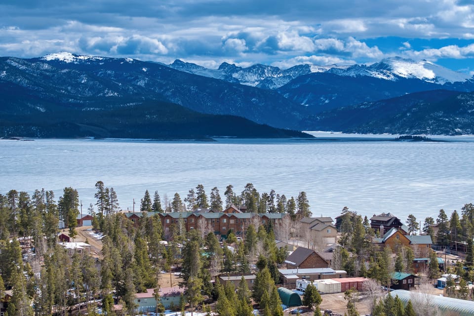 Granby Lake Shore Estates Townhome 5 located in a stunning mountain town setting with snow-capped peaks rising majestically above a pristine frozen lake, creating a breathtaking winter wonderland backdrop.