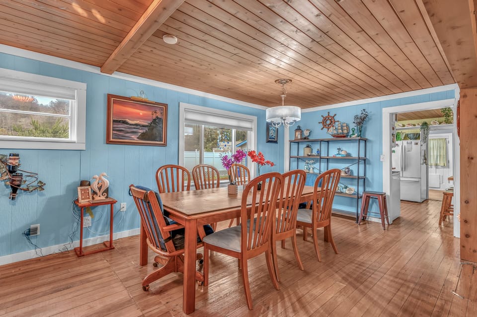 Gather around this welcoming dining table beneath stunning wood ceilings, where coastal blues and warm nautical touches create the perfect space for your meals together.