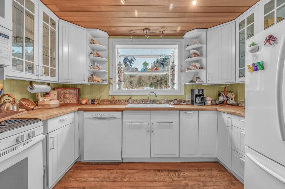 Cook your favorite meals in this bright, fully-equipped kitchen with wood countertops, open shelving for your treasures, and a garden window.