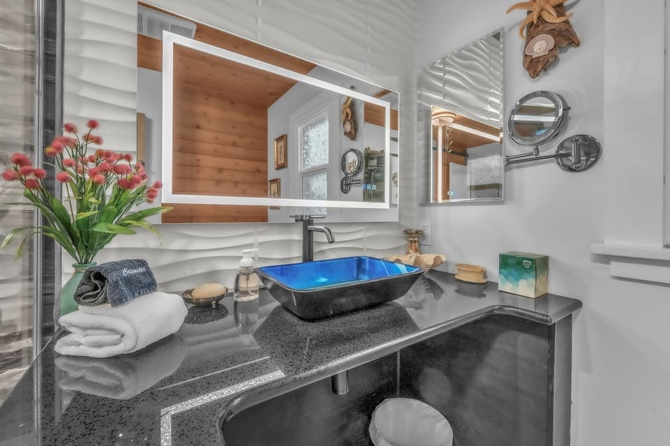 Refresh in your stylish bathroom featuring a striking blue vessel sink, granite countertop, and modern amenities.