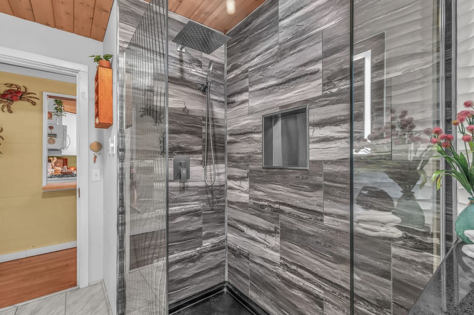 Step into your luxurious glass-enclosed shower featuring stunning marble-inspired tile walls and rainfall showerhead for ultimate relaxation.