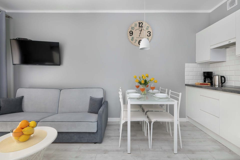 This view features a grey sofa and a small glass coffee table with a decorative bowl. The kitchen area on the right has white cabinets and a stovetop.