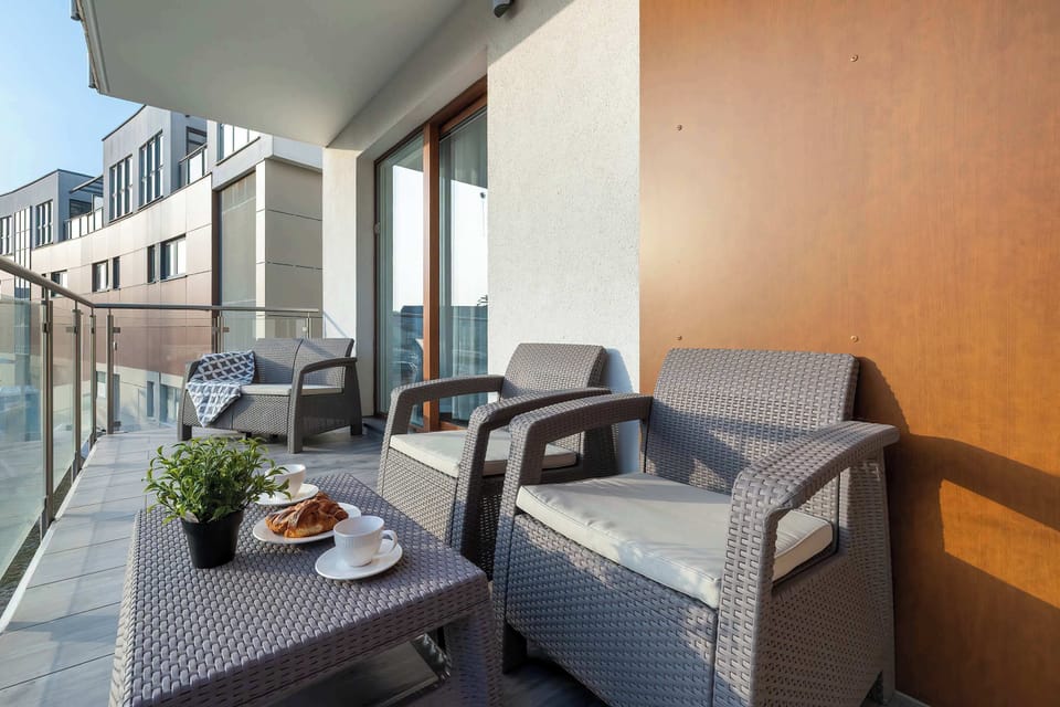 A cozy balcony with technorattan garden furniture and soft cushions. Coffee and snacks are prepared on the table, perfect for relaxing outdoors.