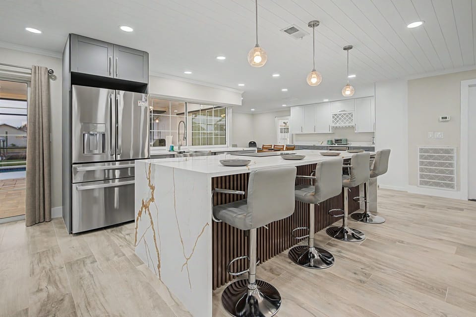 Gather around the sleek waterfall-edge island where modern elegance meets everyday comfort. Stainless steel appliances, bright pendant lighting, and soft neutral tones create the perfect setting for your culinary adventures.