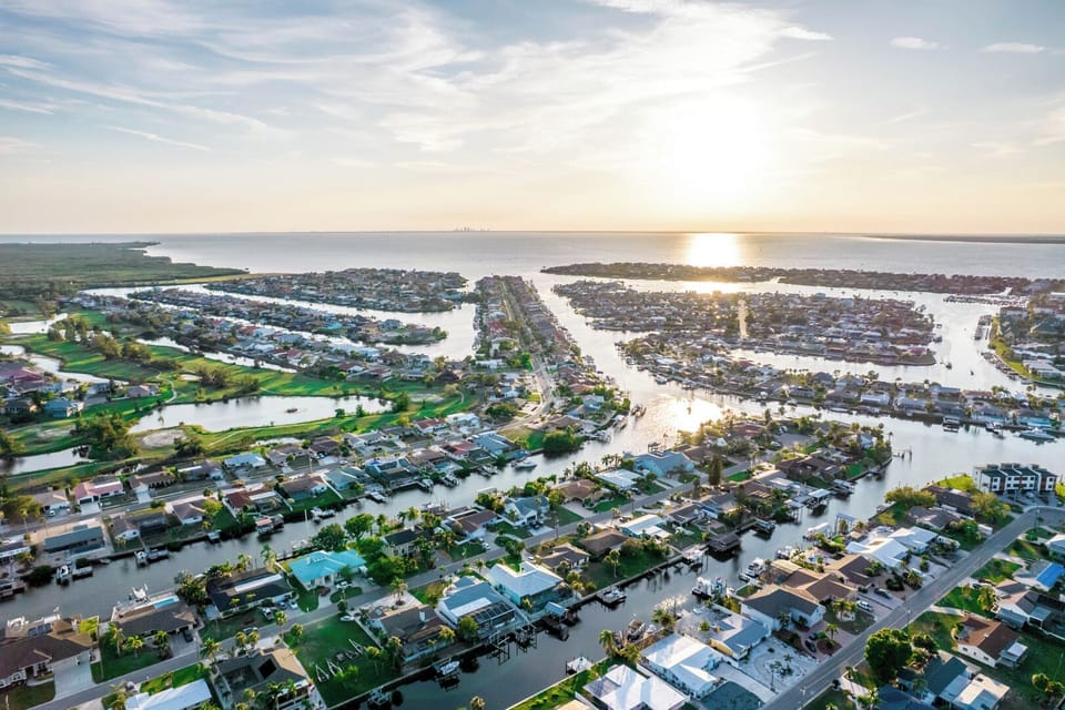 Aerial view of a picturesque waterfront community with canals winding through residential neighborhoods at golden hour.