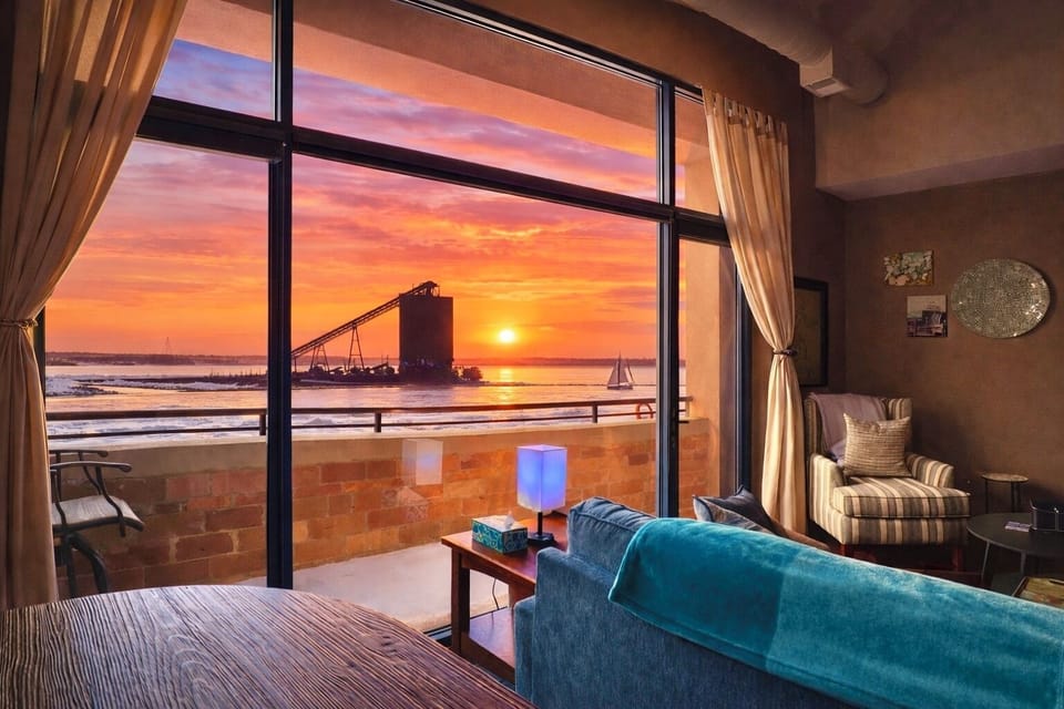 Gigantic windows frame a stunning sunset over the water, with a private balcony just steps away. Enjoy peaceful evenings watching sailboats glide by and the sky light up in warm coastal colors.