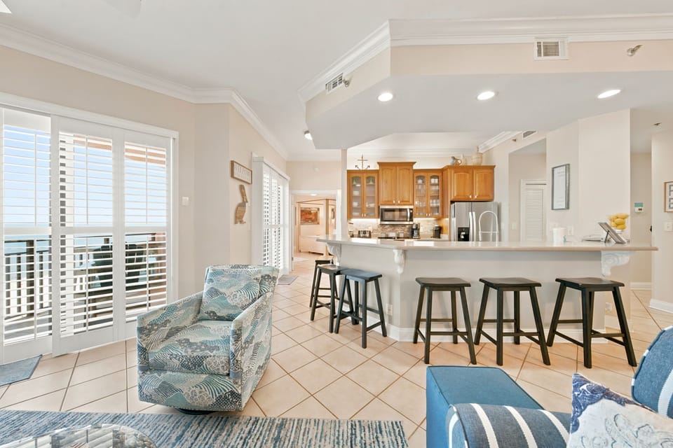 SeaChase 1104C-Relax in your open-concept living space, where coastal blue seating flows into a bright kitchen with breakfast bar—perfect for morning coffee or casual meals together.