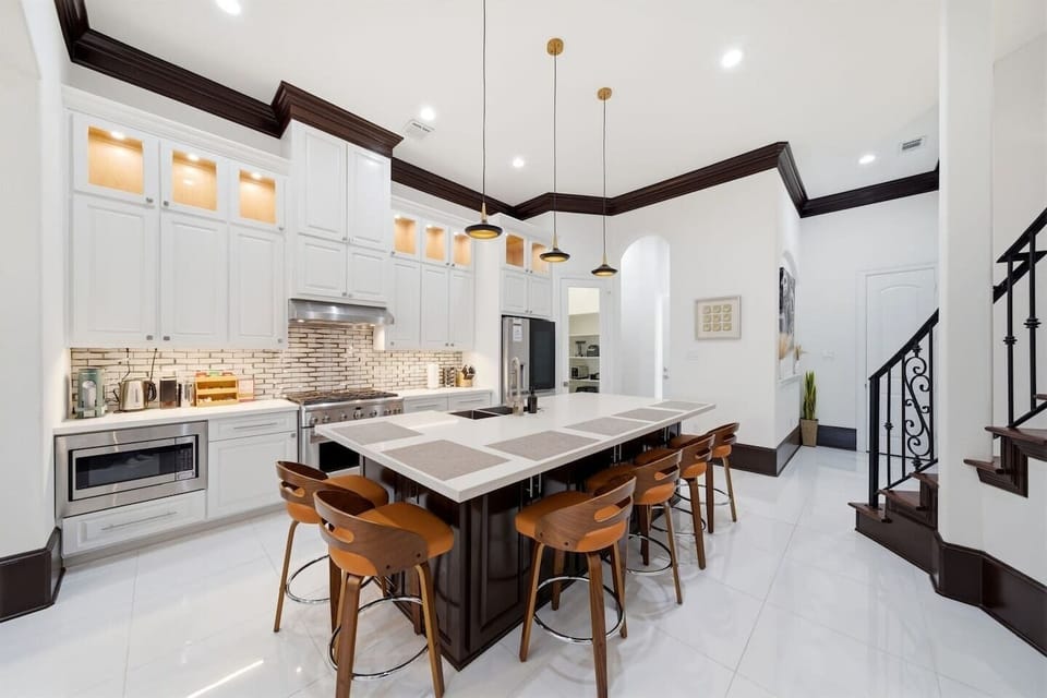 A beautifully designed chef’s kitchen that feels as elevated as it is functional—anchored by a stunning oversized island and warm designer lighting. Fully stocked for everything from casual mornings to curated dinners, featuring premium appliances. 