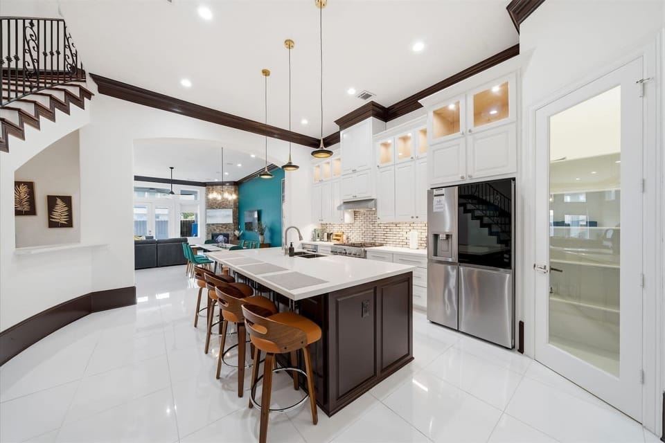 A beautifully designed chef’s kitchen that feels as elevated as it is functional—anchored by a stunning oversized island and warm designer lighting. Fully stocked for everything from casual mornings to curated dinners, featuring premium appliances. 