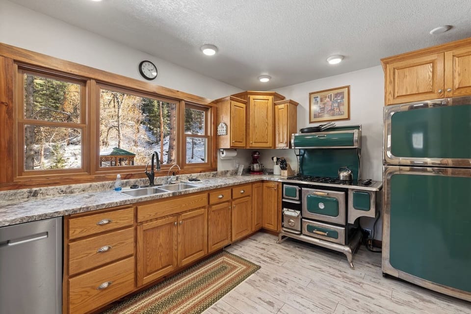 Prepare meals with charm in the kitchen, featuring warm wooden cabinetry and a vintage green stove that adds character.