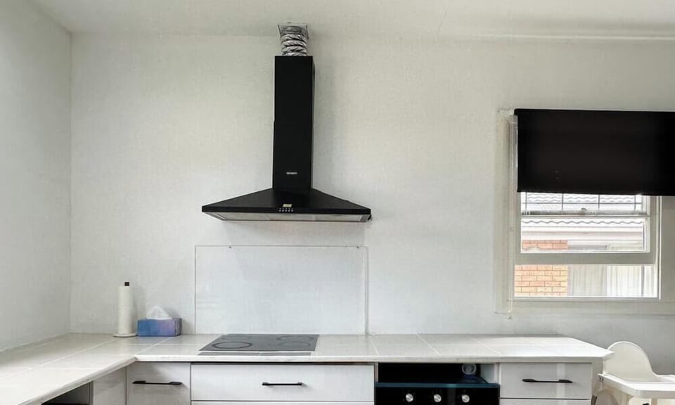 A polished and well-equipped kitchen corner featuring a black range hood and light-toned cabinetry.