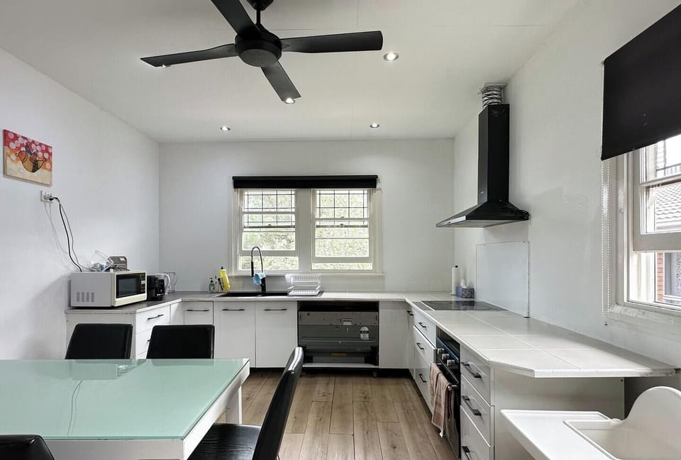 A clean and functional kitchen area equipped with modern white cabinetry and a dining table.